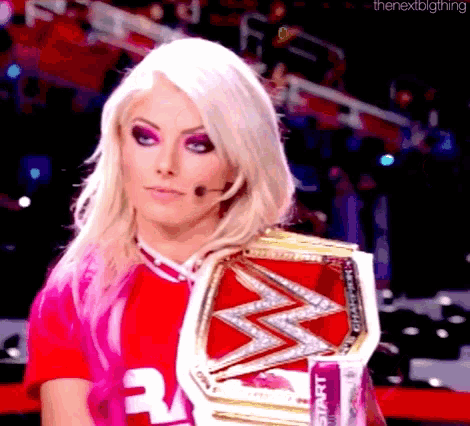 a woman in a pink shirt is holding a wrestling championship .