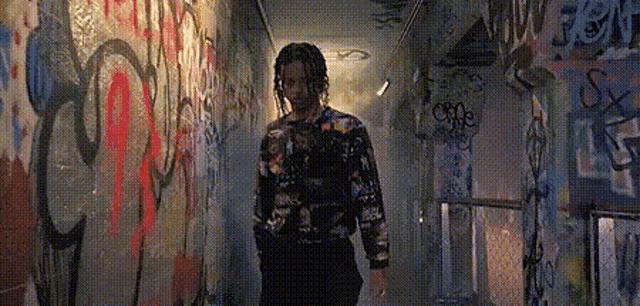 a person is walking down a hallway with graffiti on the walls .