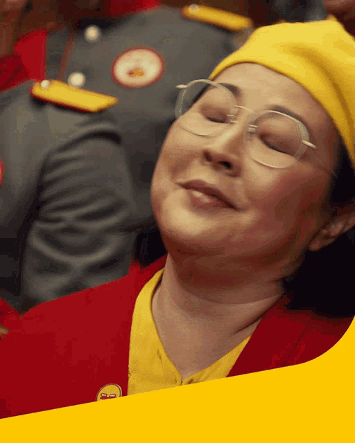a woman wearing glasses and a yellow hat with the letter s on it