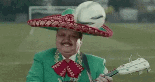 a man wearing a green suit and sombrero is playing a guitar .
