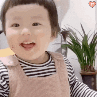 a baby is smiling and looking at the camera while wearing a striped shirt .