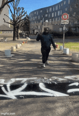 a man is walking down a street with graffiti on the side of it