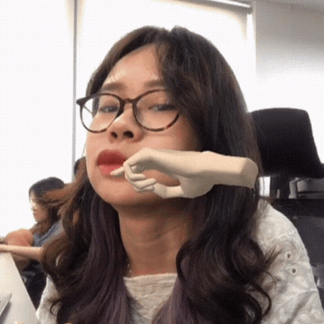 a woman wearing glasses has a hand on her mouth