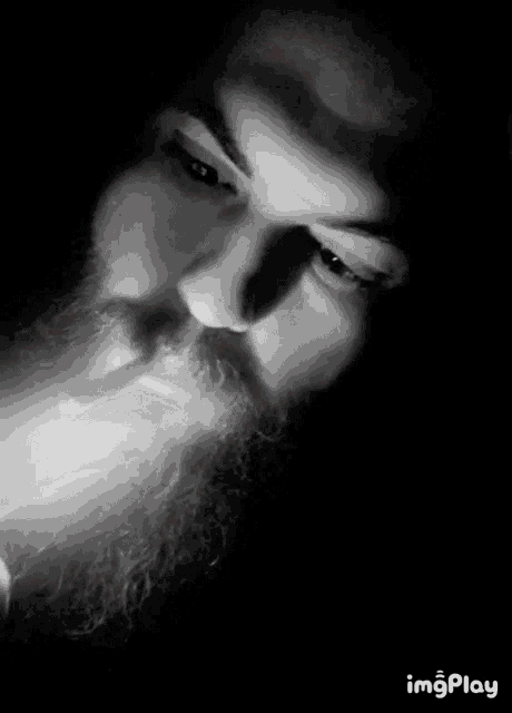 a man with a beard and red eyes is smoking a cigarette