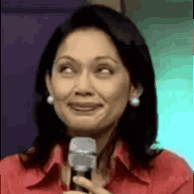 a woman is smiling while holding a microphone and making a funny face .