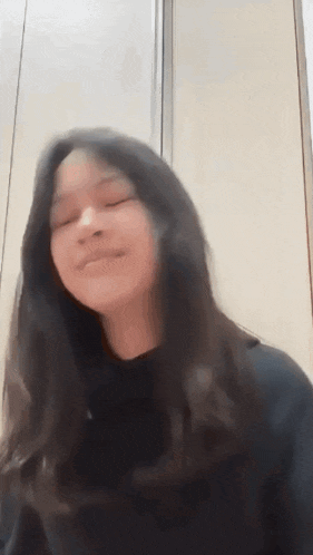 a young girl with long hair is making a funny face .