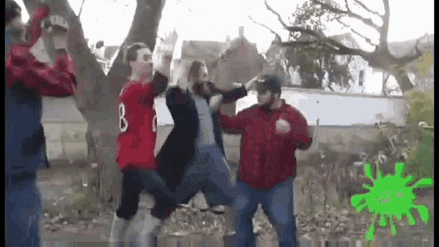 a group of men are dancing in front of a tree .