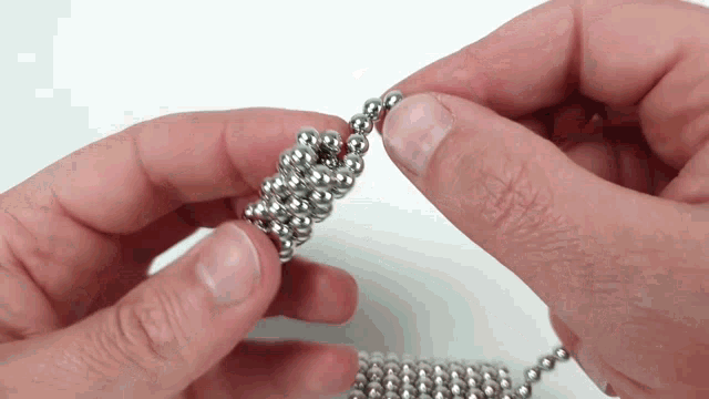 a person holding a bunch of metal beads in their hands
