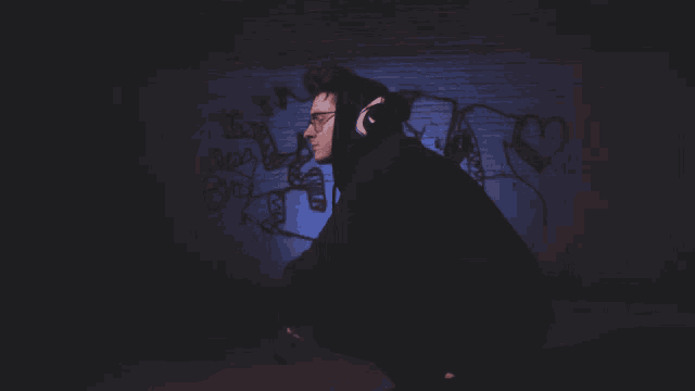 a man wearing headphones stands in front of a wall with graffiti that says i love you
