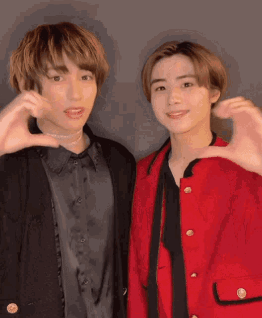 two young men are making a heart with their hands