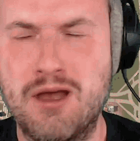 a man with a beard is wearing headphones and his eyes are closed