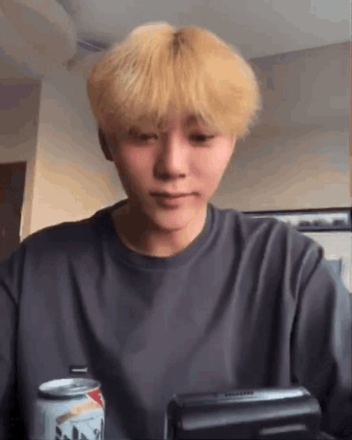 a man with blonde hair is holding a can of soda