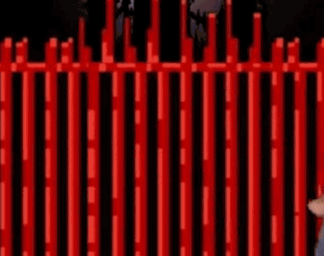 a man in a blue shirt is walking behind a red fence .