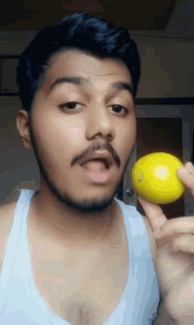 a man with a beard is holding a small yellow ball in his hand