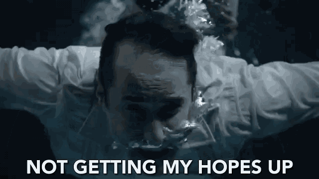 a man in a white shirt is swimming in the water with the words " not getting my hopes up " written above him .