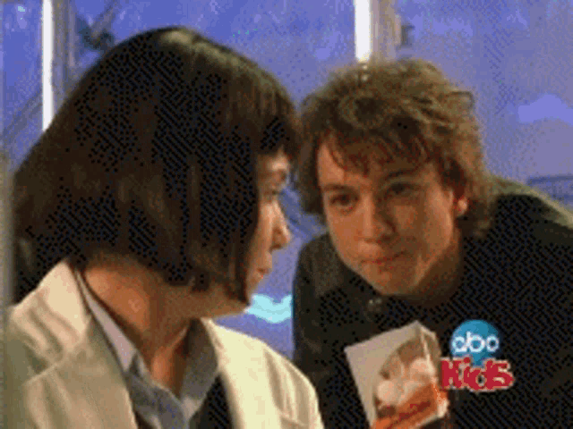 a man and a woman are looking at each other with a abc kids logo behind them
