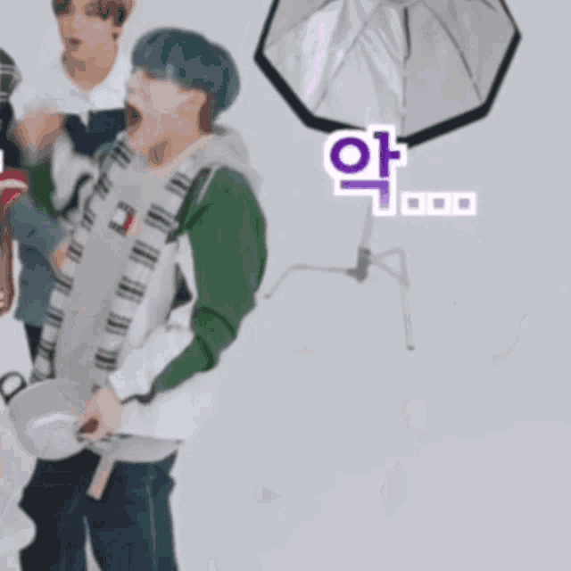 a man with blue hair is standing in front of a tommy hilfiger sweater