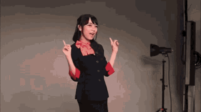 a woman in a suit and bow tie is standing in front of a camera .