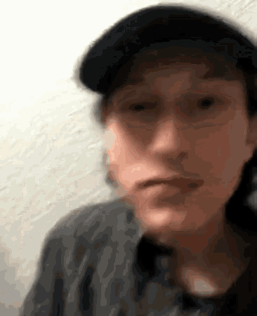 a blurry picture of a man wearing a hat and a black shirt
