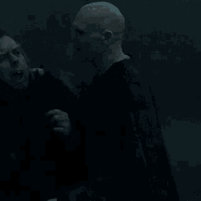 two men are fighting in the dark in a dark room .