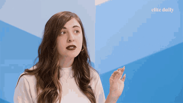 a woman in front of a blue wall with the elite daily logo