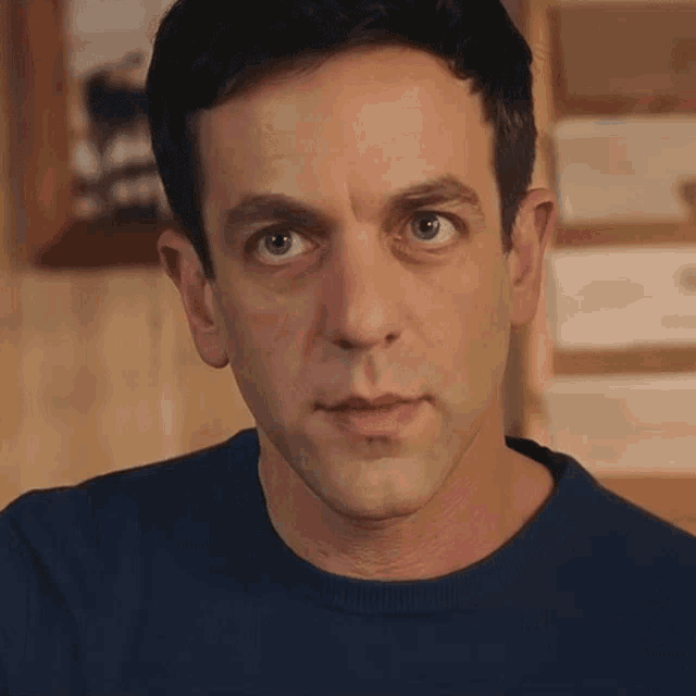 a close up of a man 's face with a blue shirt on
