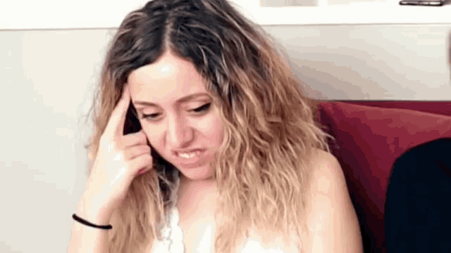 a woman sitting on a couch with her hand to her head