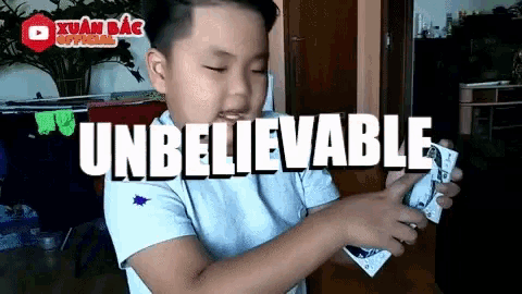 a young boy holding a playing card with the word unbelievable written on it