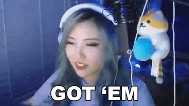 a woman wearing headphones and a cat headband is sitting in front of a microphone and saying `` got em '' .