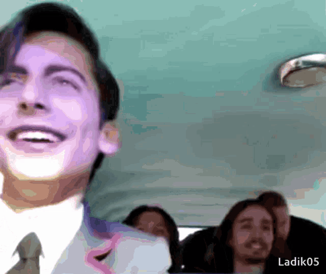 a man in a suit and tie is smiling while sitting in the back of a car