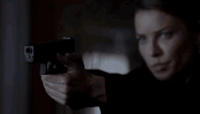 a close up of a woman holding a gun in her hand .