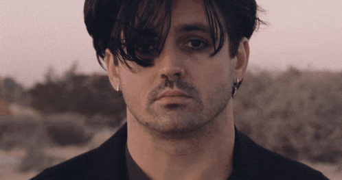 a close up of a man 's face with a beard and earrings