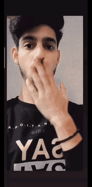 a young man wearing a yag t-shirt covering his mouth