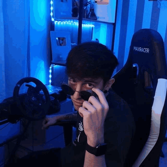 a man wearing sunglasses is sitting in a maxracer gaming chair