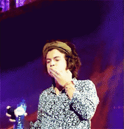 a man covering his mouth with his hand while holding a bottle