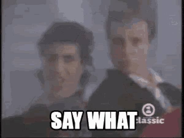 a man with a mustache is standing next to another man with a mustache and the words `` say what '' .