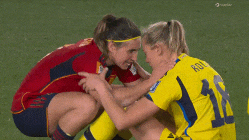 a woman in a yellow jersey with the number 11 on it is hugging another woman in a red jersey