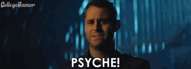 a man with his tongue out says psyche in a dark room