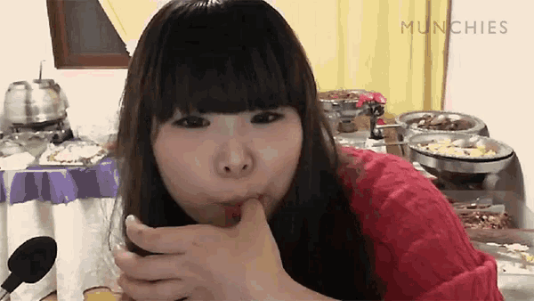 a woman in a red sweater is eating a piece of food with the words munchies above her