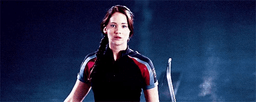 a woman in a black and red shirt is holding a bow and arrow .
