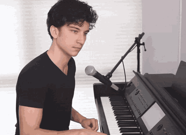 a young man playing a piano with a microphone attached