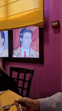a man sits at a table in front of a window with a picture of a matador on it