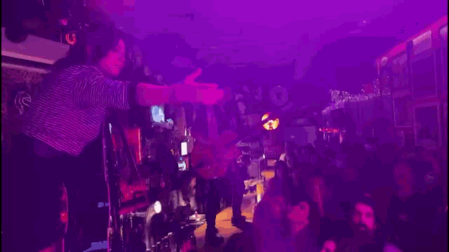 a man in a striped shirt is playing a keyboard in front of a crowd .