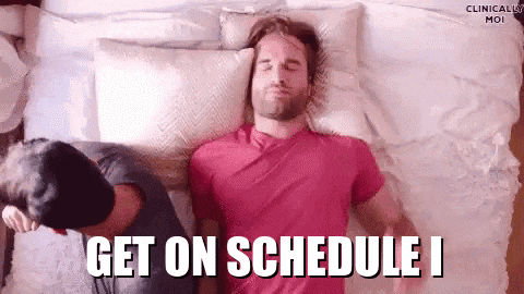 a man in a pink shirt is laying on a bed next to another man and the words get on schedule i
