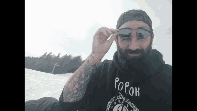 a man with a beard wearing sunglasses and a black shirt that says popoh