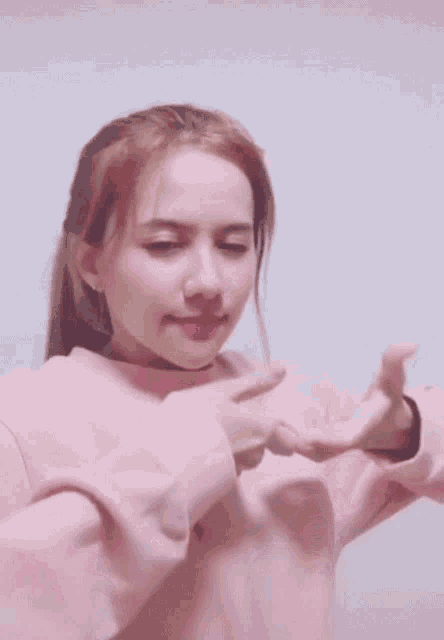 a woman wearing a pink sweater is making a funny face