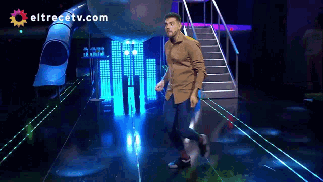 a man is dancing on a stage with eltrecetv.com in the corner