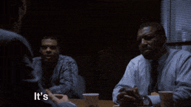 two men sitting at a table with the words " it 's when a " on the bottom