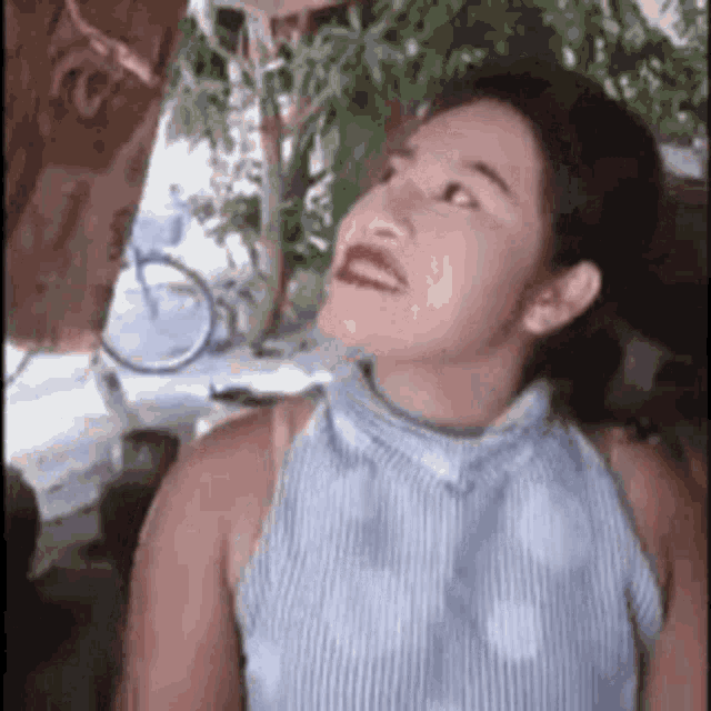 a woman in a blue and white striped shirt is looking up .