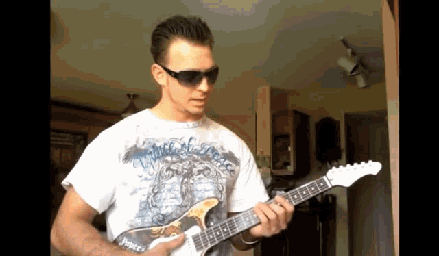 a man wearing sunglasses is playing a guitar with a shirt that says ' sniper ' on it